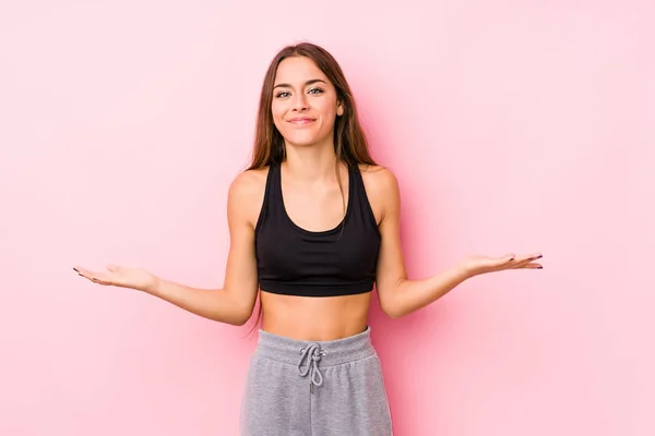 年轻的高加索健身女子 穿着粉色背景的衣服 脸上带着受欢迎的表情 — 图库照片