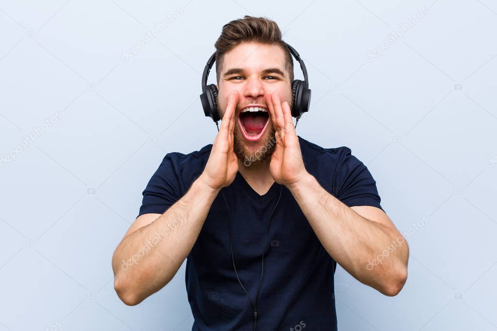 Young caucasian man listening to music shouting excited to front.