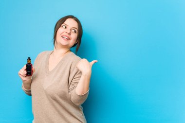 Buharlaştırıcı puanlar tutan genç, kıvrımlı bir kadın başparmağıyla uzakta, gülüyor ve kaygısız..