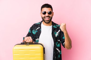 Bir bavul tutan genç latin adam tasasız ve heyecanlı bir şekilde tezahürat yapıyor. Zafer konsepti.