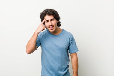 Beyaz arka planda genç ve yakışıklı bir adam işaret parmağıyla hayal kırıklığı gösteriyor..