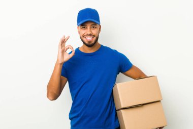 Genç Güney Asyalı teslimatçı neşeli ve kendinden emin, iyi bir jest yapıyor..