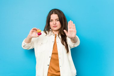 Genç, kıvrımlı bir kadın elinde kurabiyelerle dur işareti göstererek seni engelliyor..