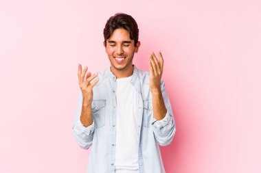 Pembe arka planda poz veren beyaz bir genç neşeli bir şekilde gülüyor. Mutluluk kavramı.