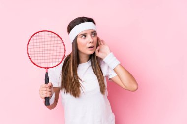 Badminton oynayan beyaz bir kadın bir dedikoduyu dinlemeye çalışıyor..