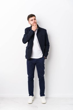Tam vücut Kafkasyalı genç adam şüpheli ve şüpheci bir ifadeyle yana bakıyor..
