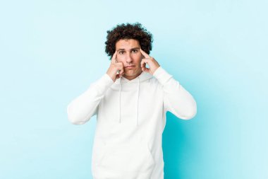 Mavi bir geçmişi olan genç sporcu bir adam bir göreve odaklanmış, işaret parmaklarını işaret ediyor..