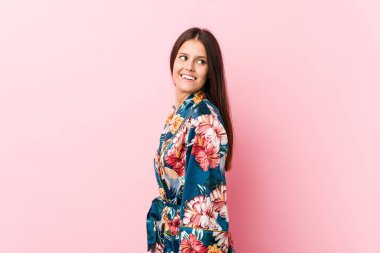 Kimono pijama giyen beyaz bir kadın gülümseyen, neşeli ve keyifli bir kenara bakar..
