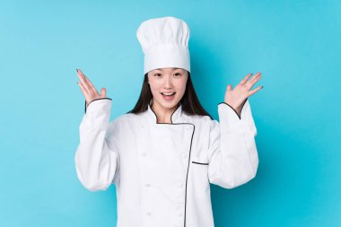 Genç Çinli aşçı kadın yalnız başına hoş bir sürpriz bekliyor, heyecanlı ve el kaldırıyor..