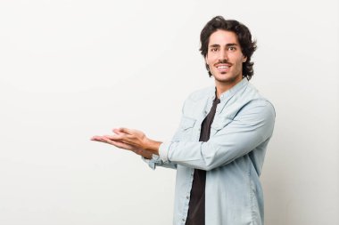 Beyaz arka planda genç ve yakışıklı bir adam avucunun içinde bir kopya alanı tutuyor..