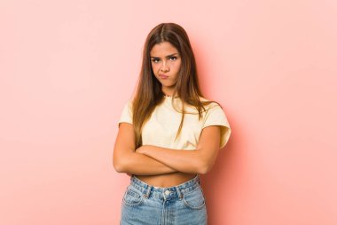 Young slim woman frowning face in displeasure, keeps arms folded.