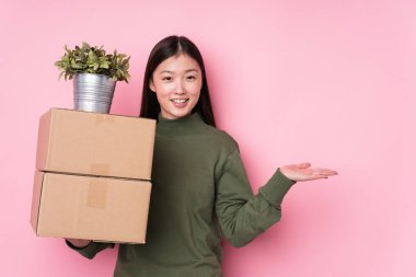 Elinde kutular olan genç Çinli bir kadın avucunun içinde fotokopi odasını gösteriyor ve belinde başka bir el tutuyor..