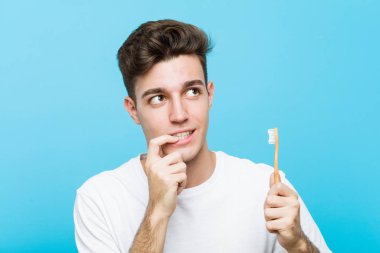 Elinde diş fırçası tutan genç beyaz bir adam pijama ve uyku maskesi takmış genç Hintli bir kadın bir yastık tutuyor rahat bir şekilde fotokopi odasına bakan bir şeyi düşünüyor.. 