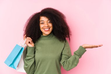 Genç afro kadın alışverişte izole edilmiş genç afro kadın yalnız başına bir afro kadın alıyor. Elinde yalnız bir gül tutuyor. Bir avuç içinde fotokopi odası var ve belinde başka bir el tutuyor.