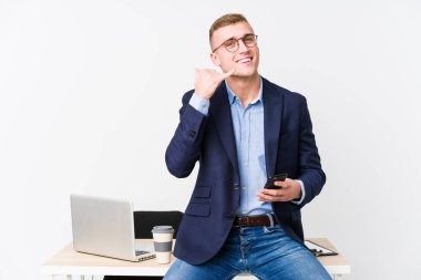 Bilgisayarlı genç bir iş adamı cep telefonu hareketini parmaklarıyla gösteriyor..