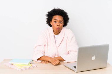 Orta yaşlı Afrikalı Amerikalı kadın evde tek başına çalışıyor omuz silkiyor ve gözleri açık..