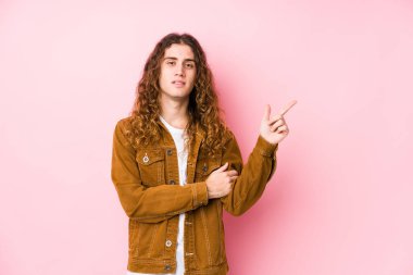 Genç, uzun saçlı, yalnız poz veren, gülümseyen, işaret parmağıyla işaret eden adam..