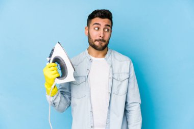 İzole edilmiş ütü yapan genç bir adamın portresi. Kafası karışmış, kararsız ve emin değil..