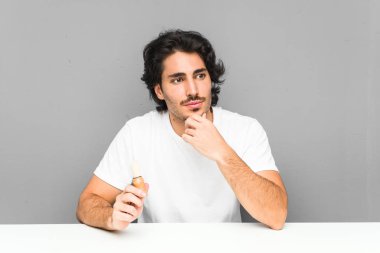 Sakalını kesen genç adam şüpheli ve şüpheci bir ifadeyle yana bakıyor..