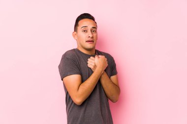 Pembe arka planda poz veren seni gidi Latin adam, korkmuş ve korkmuş..