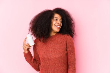 Vitaminlerini tutan genç afro bir kadın. Vitaminlerini tutan genç bir afro kadın. Gülümsüyor, neşeli ve keyifli..