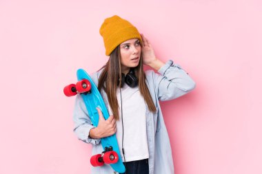 Genç patenci kadın elinde patenle bir dedikoduyu dinlemeye çalışıyor..