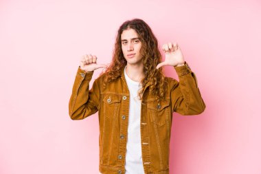 Uzun saçlı yalnız poz veren genç adam kendini gururlu ve kendinden emin hissediyor, örnek olarak..