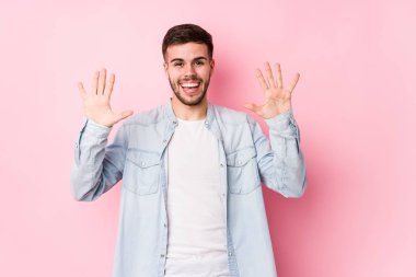 Beyaz arka planda poz veren beyaz tenli genç iş adamı 10 numarayı elleriyle gösteriyor..