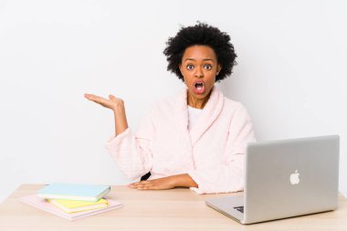 Orta yaşlı Afro-Amerikalı kadın evde çalışıyor. Palmiye üzerinde fotokopi yeri tutmaktan etkilenmiş..