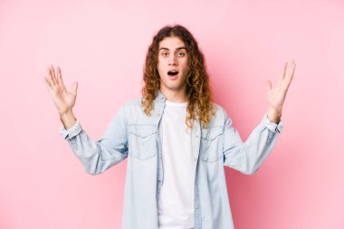 Uzun saçlı adam yalnız poz veriyor. Hoş bir sürpriz bekliyor. Heyecanlı ve el kaldırıyor..