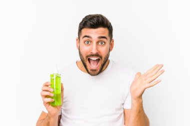 Genç, beyaz bir adam elinde aloe vera ile nemlendirici tutarak zaferi ya da başarıyı kutluyor.