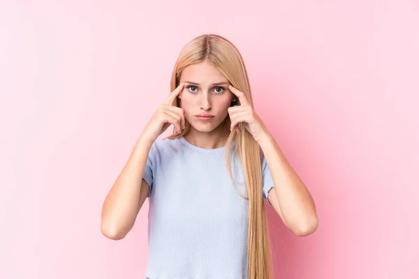 粉红背景的年轻金发女子专注于一项任务 食指指向头 — 图库照片