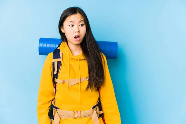 Young chinese backpacker woman isolated being shocked because of something she has seen.