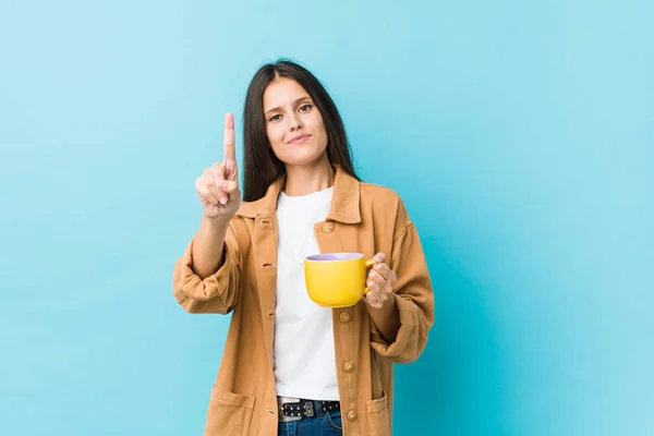 年轻的高加索女人拿着咖啡杯 用手指拿着第一杯咖啡 — 图库照片