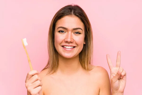 歯ブラシを持っている若い白人女性は指で2番目を示す単離された — ストック写真