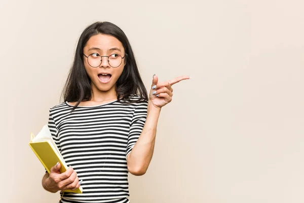Νεαρή Ασιάτισσα Φοιτήτρια Που Κρατάει Βιβλίο Και Δείχνει Πλάι — Φωτογραφία Αρχείου