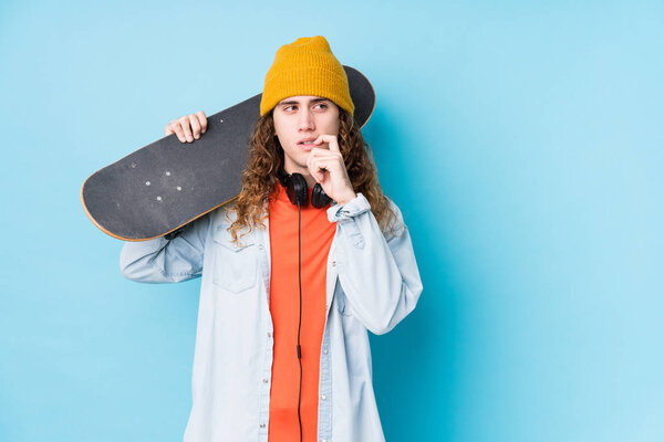 Young caucasian skater man isolated relaxed thinking about something looking at a copy space.