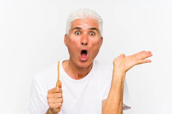 Senior Caucasiano Homem Segurando Teethbrush Isolado Impressionado Segurando Espaço Cópia — Fotografia de Stock