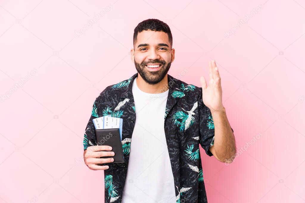 Young arabian cool man holding a boarding passes isolated receiving a pleasant surprise, excited and raising hands.