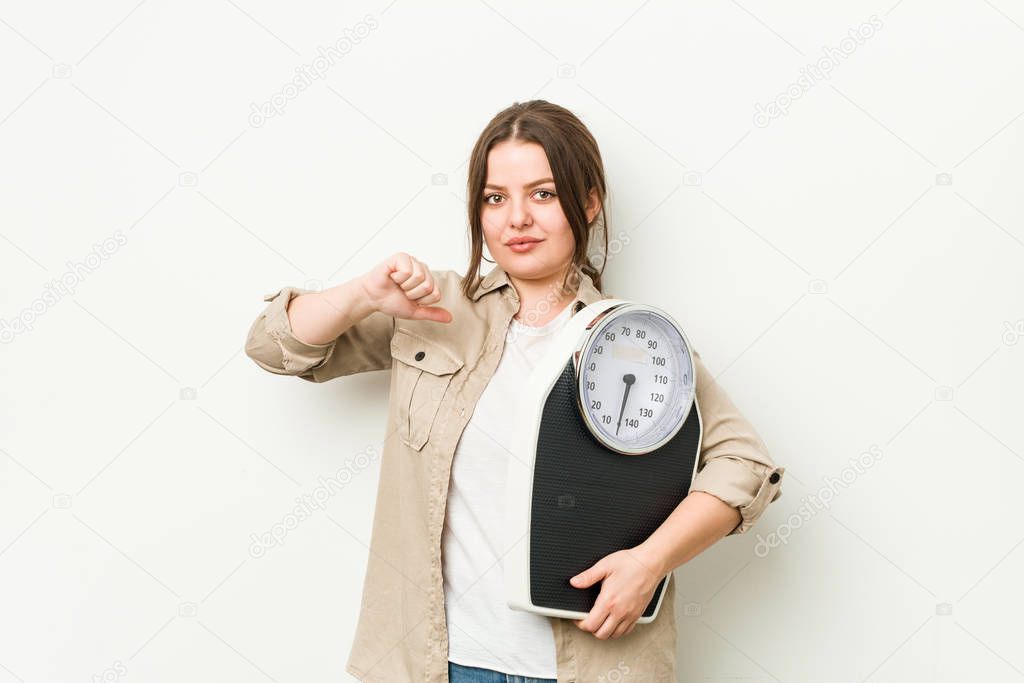Young curvy woman holding a scale feels proud and self confident, example to follow.