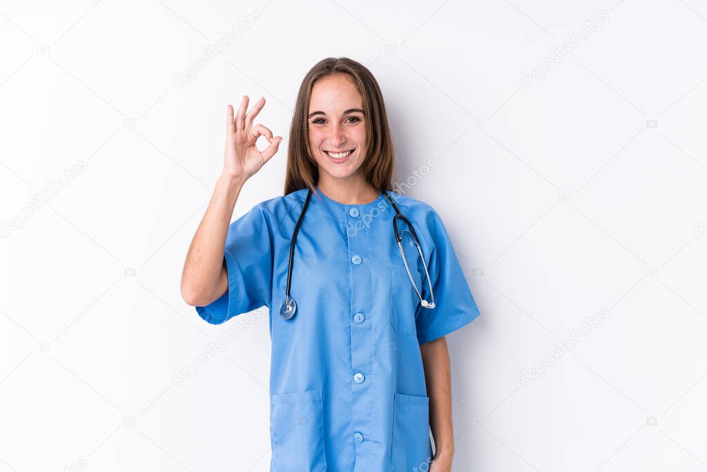 Young nurse woman isolated cheerful and confident showing ok gesture.