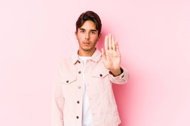 Pembe arka planda poz veren genç beyaz bir adam elini uzatmış, dur işareti göstererek seni engelliyor..