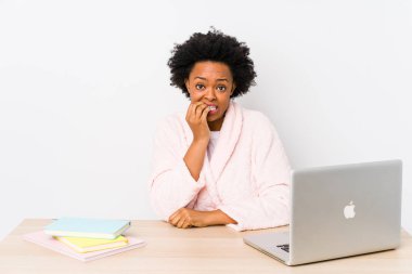 Orta yaşlı Afro-Amerikalı kadın evde çalışıyor, tırnak yiyor, gergin ve endişeli..