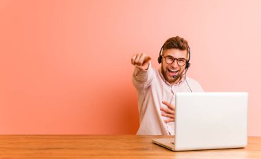 Çağrı merkezinde çalışan genç bir adam başparmağı uzakta, gülüyor ve kaygısız..