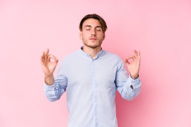 Pembe arka planda poz veren genç beyaz adam sıkı çalışma gününden sonra dinleniyor. Yoga yapıyor..