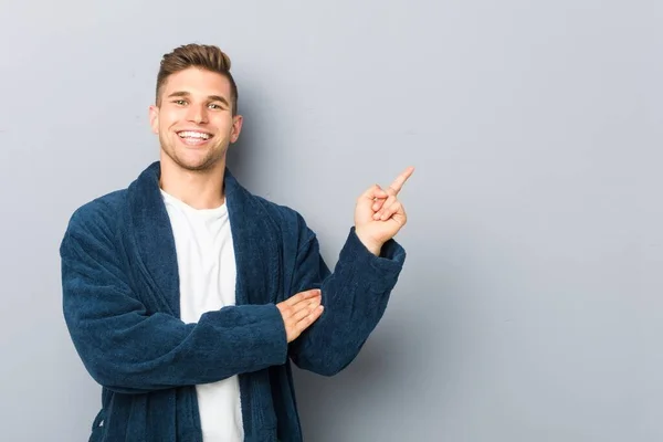 Young Caucasian Man Wearing Pajama Smiling Cheerfully Pointing Forefinger Away — 스톡 사진