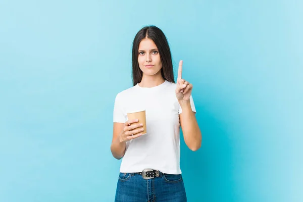 Joven Mujer Caucásica Sosteniendo Café Para Llevar Mostrando Número Uno —  Fotos de Stock