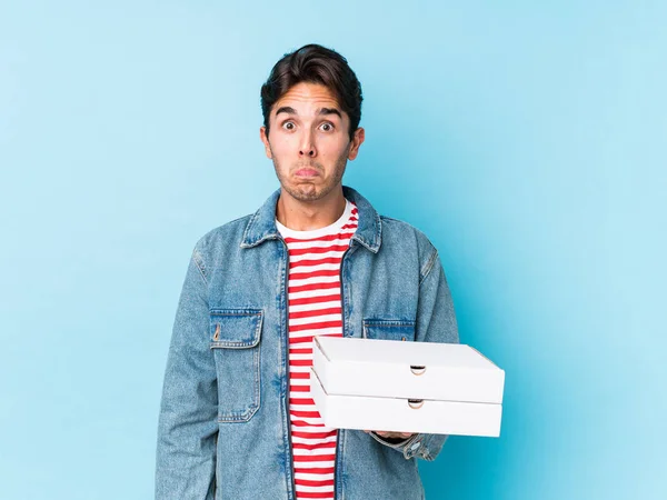 Young Caucasian Man Holding Pizzas Isolated Shrugs Shoulders Open Eyes — 스톡 사진