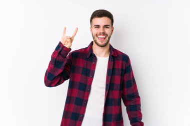 Beyaz arka planda yalnız poz veren genç beyaz bir adam devrim konsepti olarak boynuzlarını gösteriyor..