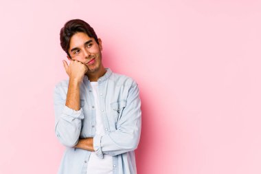Pembe arka planda yalnız poz veren beyaz bir genç üzgün ve dalgın bir şekilde fotokopi odasına bakıyor..
